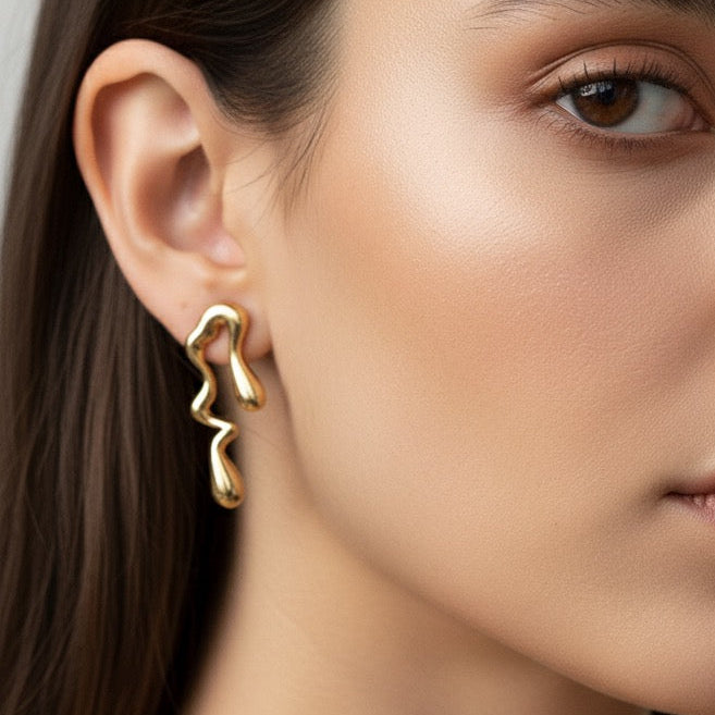 Close-up of a woman wearing gold earrings with a neutral background